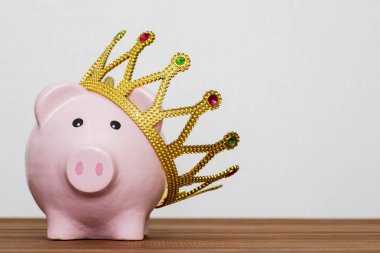 Finansal Galibi veya para tasarruf kavramı, mutlu pembe ahşap masa, en iyi gelecekte yatırım altın bir taç giyen kumbara gülümseyen kralı