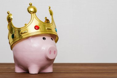 Finansal Galibi veya para tasarruf kavramı, mutlu pembe ahşap masa, en iyi gelecekte yatırım altın bir taç giyen kumbara gülümseyen kralı