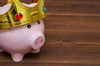 Finansal Galibi veya para tasarruf kavramı, mutlu pembe ahşap arka plan üzerinde en iyi gelecekte yatırım altın bir taç giyen kumbara gülümseyen kralı