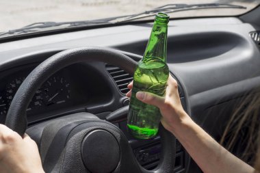 Bir araba sürüş sırasında bira şişesi tutan kadın