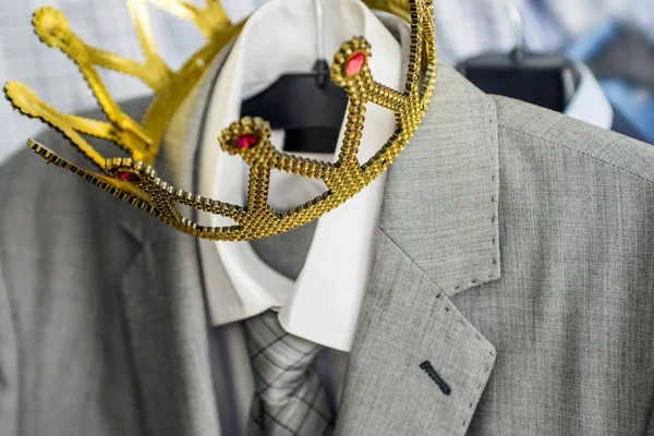 Business suit with a gold crown hanging on a hanger. Clothing is a successful person. Business concept. Metaphor