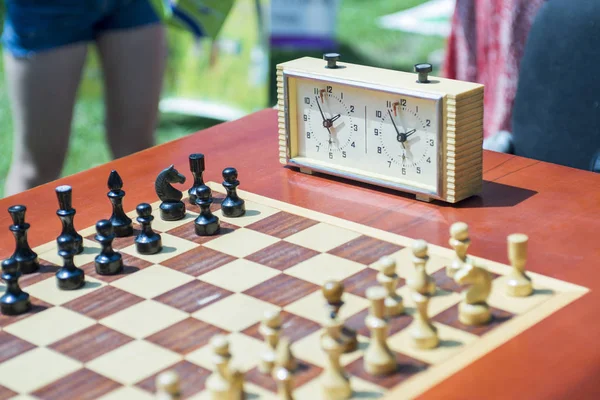 Chess board with pieces and clock on wooden desk In connection with the chess tournament. Outdoors chess competition