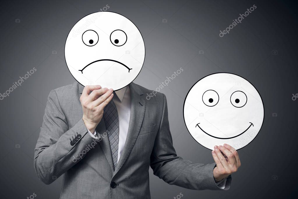 Businessman holding smile and sad mask. Conceptual image of a man changing his mood from bad to good