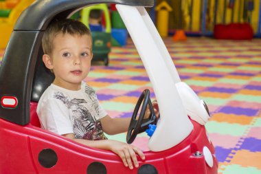 Kırmızı oyuncak araba kapalı Bahçesi, küçük çocuk. Çocuk Çocuk arabada