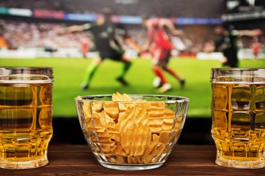 İki bardak soğuk bira ve cips, futbol maçı arka planda