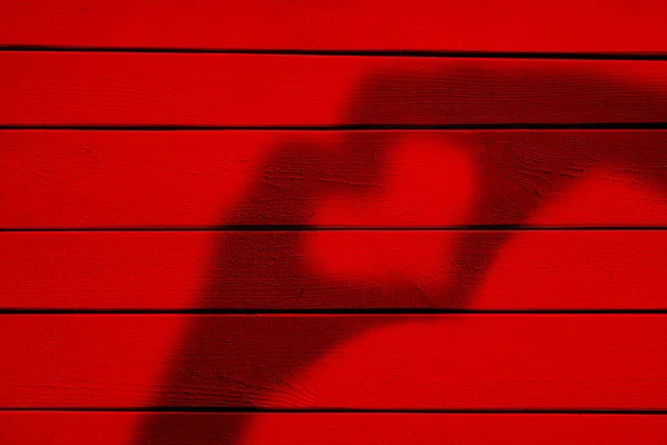 Zwei Hände Bilden Einen Herzschatten Auf Rotem Holzhintergrund — Stockfoto