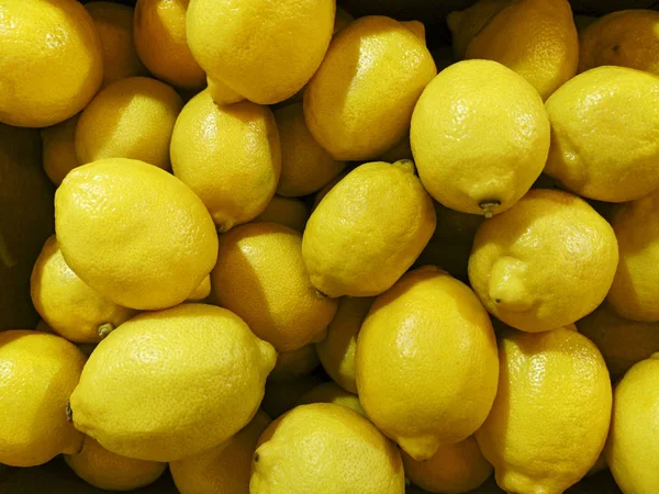 Lot of bright yellow lemons in supermarket. Lemon harvest. Many yellow lemons