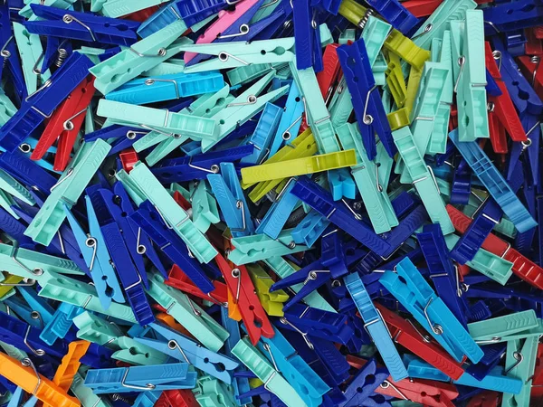 Many different colored plastic clothes pegs close up. Lots of clothespins