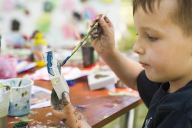 Bir oyuncak bir çocuk elinde bir fırça ile boyar. Püskül resimdeki çocuk