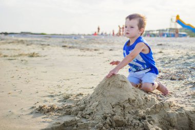 Küçük bir şirin bebek çocuk bir deniz kenarında bir plajda oynuyor. Sandcastle sahilde bina çocuk