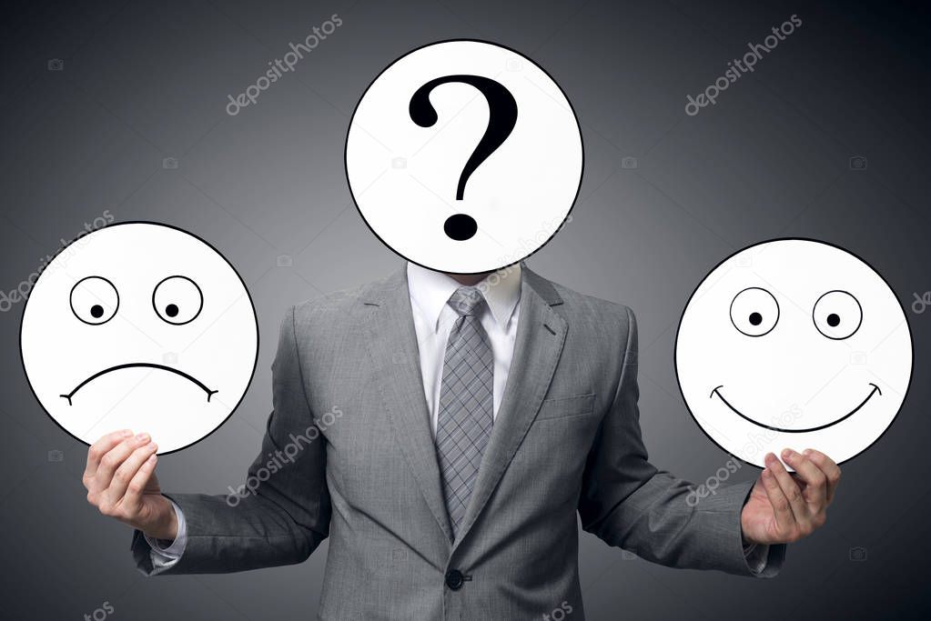 Businessman with mask of different emotions. Businessman holding smile and sad mask. Conceptual image of a man changing his mood from bad to good