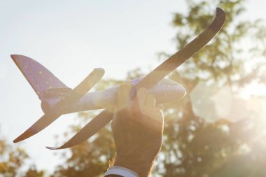 Adam oyuncak uçak ile günbatımı ve yolculuk hayalleri çalış. Küçük uçak elinle kapat. El - seyahat ve rüyalar sembolü oyuncak uçak