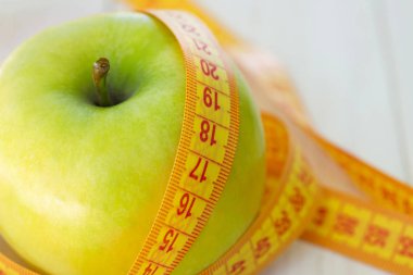 Diyet kavramı. Teyp ölçme ile yeşil elma. Yeşil elma ölçülen metre, spor elma