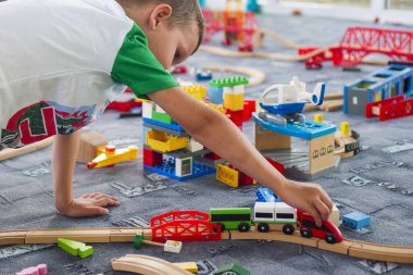Tahta tren ile yere oynayan küçük çocuk. Küçük çocuk ahşap tren ile oynarken ayarla
