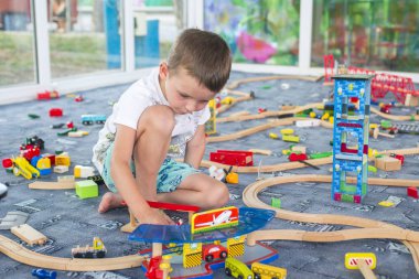 Tahta tren ile yere oynayan küçük çocuk. Küçük çocuk ahşap tren ile oynarken ayarla