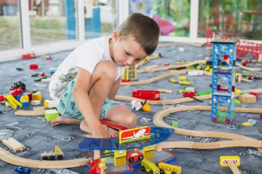 Tahta tren ile yere oynayan küçük çocuk. Küçük çocuk ahşap tren ile oynarken ayarla