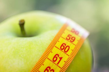 Diyet kavramı. Teyp ölçme ile yeşil elma. Yeşil elma ölçülen metre, spor elma