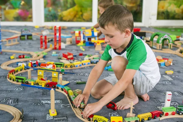Tahta tren ile yere oynayan küçük çocuk. Küçük çocuk ahşap tren ile oynarken ayarla