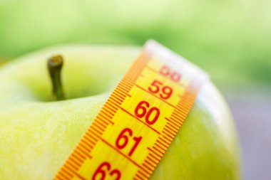 Diyet kavramı. Teyp ölçme ile yeşil elma. Yeşil elma ölçülen metre, spor elma