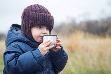 bir fincan çay açık havada tutan küçük bir çocuk. Çocuk çay içer