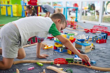 Tahta tren ile yere oynayan küçük çocuk. Küçük çocuk ahşap tren ile oynarken ayarla