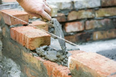 Çimento işçi tuğla duvar dış duvarda yükleme. Profesyonel inşaat işçisi tuğla döşeme. Çimento işçi tuğla inşaat sitede yükleme