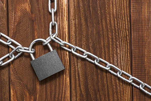 Padlock and chain on wooden background. Metal chain and locked padlock on wooden background