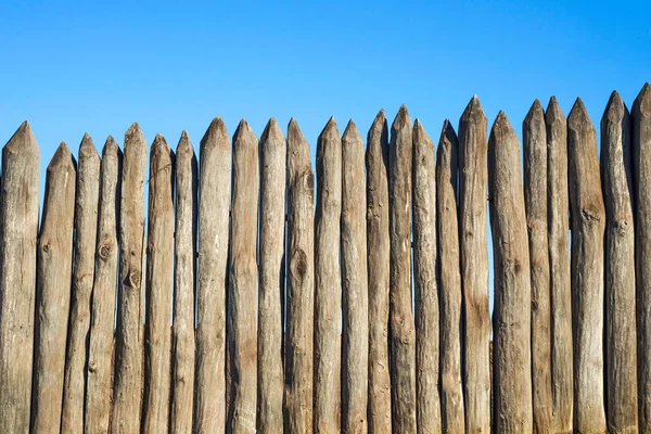 青空に鋭い木の杭のフェンス 木製フェンス縦ログ空侵略者や野生動物保護に対する指摘 — ストック写真