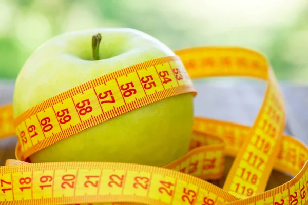 木製の背景に巻尺とグリーンアップル リンゴと木製のテーブル ミシン巻尺 重量を失うし 重量を失う 低カロリーのリンゴを食べる — ストック写真