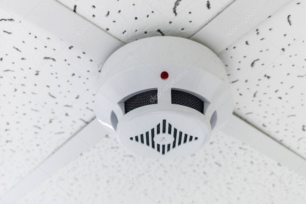 Modern smoke sensor hanging on ceiling. Temperature gage circular wall.The wall of the smoke sensor on the ceiling of the circular