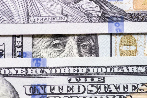 Benjamin Franklin\'s eyes between hundred dollar banknotes close-up. 100 dollar bill with only eyes of Benjamin Franklin