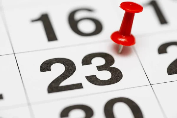 Pin on the date number 23. The twenty third day of the month is marked with a red thumbtack. Pin on calendar