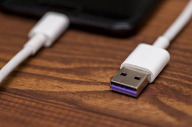 Ahşap masa üzerinde Usb kablosuyla smartphone. Akıllı telefon veya tablet hazır veri aktarımı veya pil şarj için Usb kablosu ile