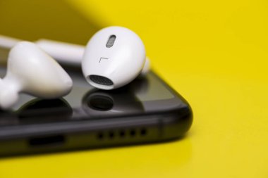 Renk arka plan üzerinde kulaklık ile akıllı telefon. Akıllı telefon ve kulaklık sarı zemin üzerine. Sarı bir arka plan üzerinde kulaklık ile akıllı telefon yakın çekim