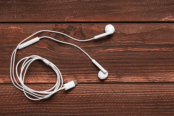 Ahşap arka plan üzerinde beyaz kulaklık. Beyaz kulaklık kopya alanı ile ahşap kurullarında. Kişisel ses aygıtı