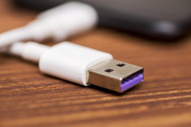 Ahşap masa üzerinde Usb kablosuyla smartphone. Akıllı telefon veya tablet hazır veri aktarımı veya pil şarj için Usb kablosu ile