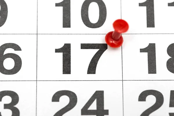 Pin on the date number 17. The seventeenth day of the month is marked with a red thumbtack. Pin on calendar. Calendar concept for important date, busy day, appointment or meeting reminder