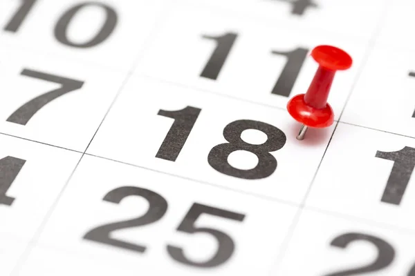 Pin on the date number 18. The eighteenth day of the month is marked with a red thumbtack. Pin on calendar. Calendar concept for important date, busy day, appointment or meeting reminder
