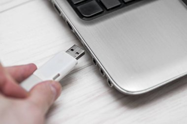 Çıkarılabilir flash disk belleği dizüstü bilgisayar Usb yuvasına takmak. Adam el ahşap beyaz arka plan üzerinde dizüstü bilgisayara Usb flash sürücü ekleme. Flash sürücüden dizüstü bilgisayara veri kopyalama