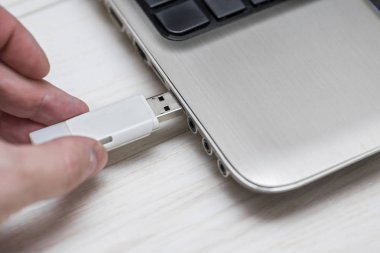 Çıkarılabilir flash disk belleği dizüstü bilgisayar Usb yuvasına takmak. Adam el ahşap beyaz arka plan üzerinde dizüstü bilgisayara Usb flash sürücü ekleme. Flash sürücüden dizüstü bilgisayara veri kopyalama