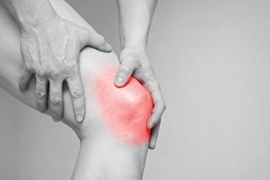 Diz ağrısı olan bir adam. Sağlık konsepti. Dizinde ağrı olan adam. Kırmızı noktalı siyah beyaz fotoğraf