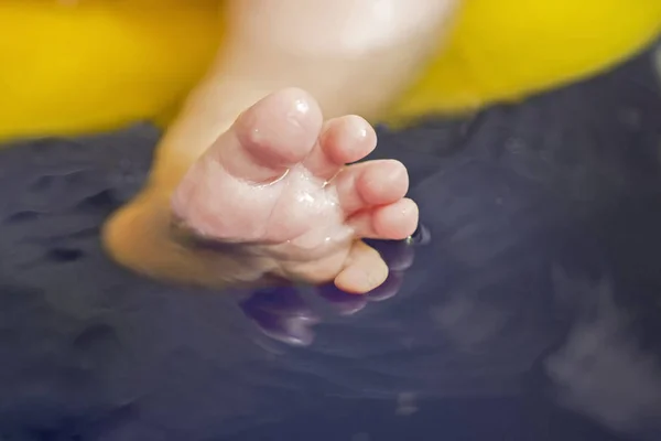 Nahaufnahme kaukasischer Kinderfüße unter Wasser in der Badewanne. Knöchel im Wasser. Eltern waschen ihrem Kind die Füße in Großaufnahme — Stockfoto