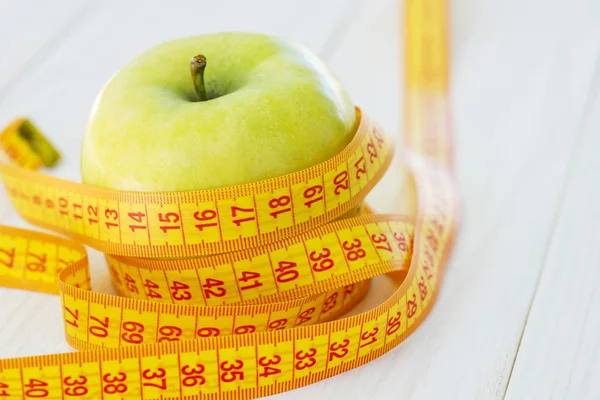 Concepto de dieta. Manzana verde con cinta métrica. Manzanas verdes midieron el medidor, manzana deportiva — Foto de Stock