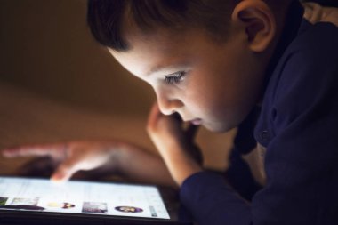 Evde gece yatakta tablet teknolojisini kullanan küçük çocuk çocuk