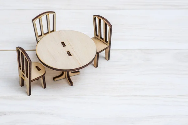 Miniature rustic wooden furniture on wooden background. Vintage table and chairs with copy space