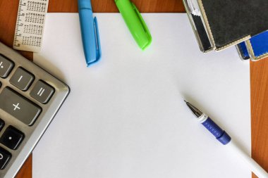 Yukarıdaki görünümden kalem, beyaz cetvel ve hesap makinesi ile ahşap masa üzerinde boş beyaz kağıt