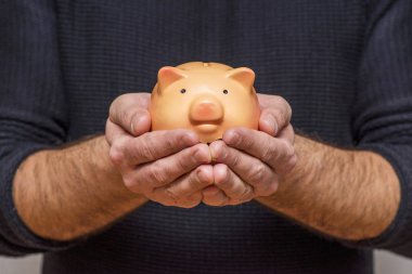 Piggy bankı tutan bir adam. Elinde bir kumbara tutan adam tasarruf ve iyi yatırımların sembolü