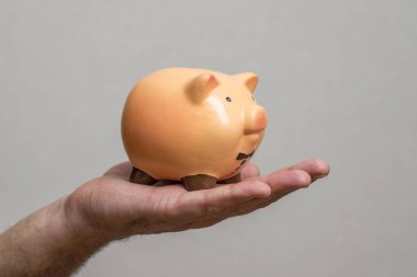 Piggy bankı tutan bir adam. Elinde bir kumbara tutan adam tasarruf ve iyi yatırımların sembolü