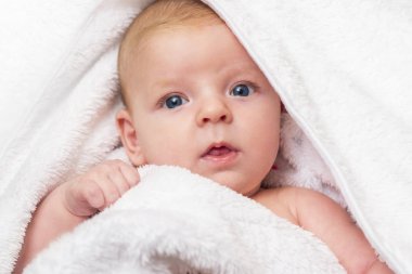 Evdeki duştan sonra havluyla mutlu bir bebek. Yeni yıkanmış beyaz havluyla yeni doğmuş bir bebek.