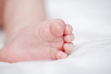 Küçük bebeğin ayakları. Beyaz battaniye nin üzerinde yeni doğmuş bebek ayakları. Minik bebek ayakları closeup